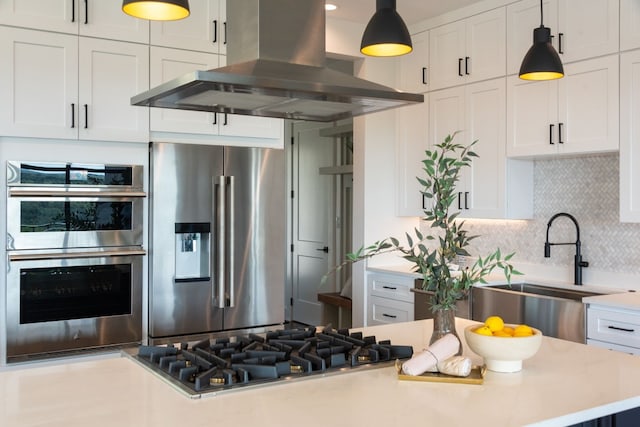 kitchen featuring island exhaust hood, white cabinets, appliances with stainless steel finishes, and backsplash