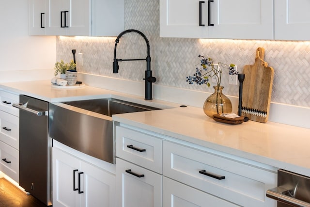 kitchen with decorative backsplash, white cabinets, hardwood / wood-style flooring, and stainless steel dishwasher