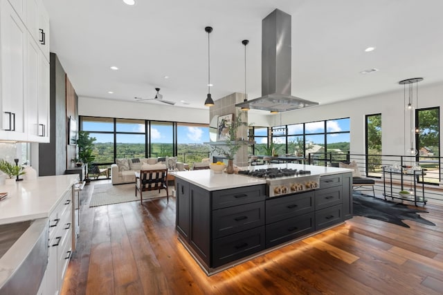 kitchen with white cabinets, wall chimney exhaust hood, a healthy amount of sunlight, and decorative light fixtures