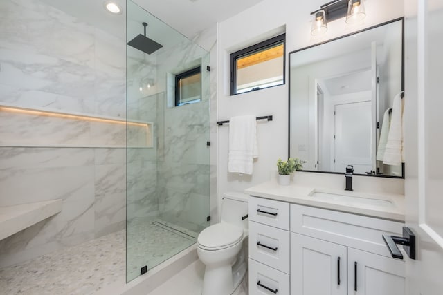 bathroom featuring vanity, tiled shower, and toilet