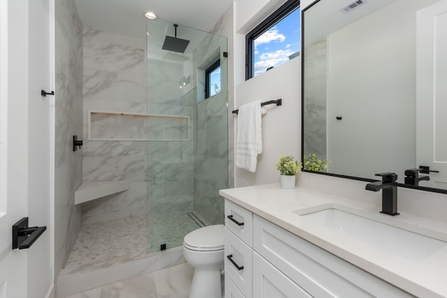 bathroom with vanity, tiled shower, and toilet