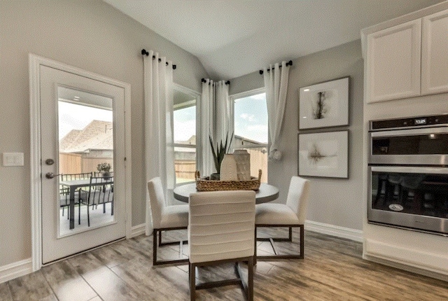 dining space featuring light hardwood / wood-style floors, vaulted ceiling, and a wealth of natural light