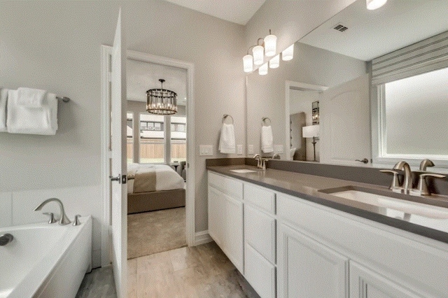 bathroom featuring a notable chandelier, a tub to relax in, hardwood / wood-style floors, and vanity