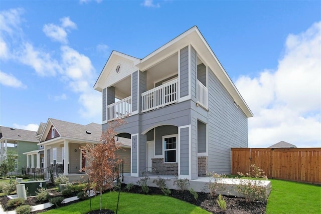 rear view of house featuring a balcony, a lawn, and a porch