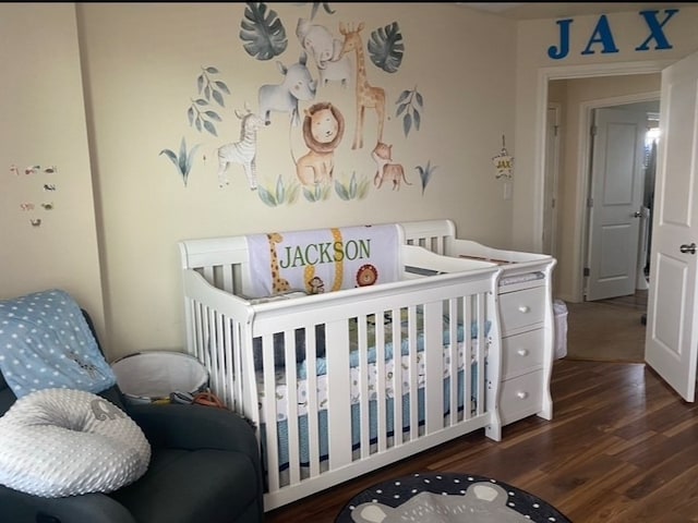 bedroom featuring dark hardwood / wood-style floors and a crib