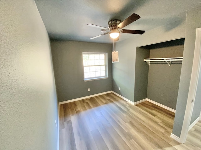 unfurnished bedroom with ceiling fan, a closet, and hardwood / wood-style floors