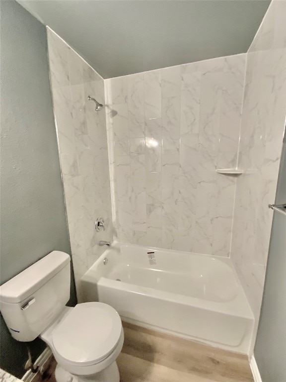 bathroom featuring hardwood / wood-style flooring, tiled shower / bath combo, and toilet