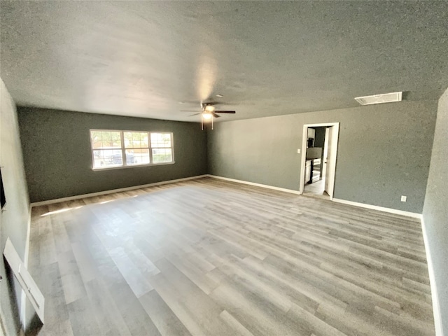 unfurnished living room with wood-type flooring, vaulted ceiling, a textured ceiling, and ceiling fan