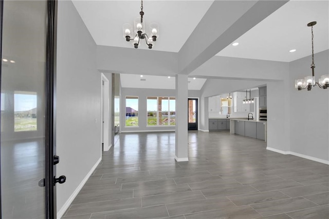 unfurnished living room with an inviting chandelier, hardwood / wood-style floors, and sink