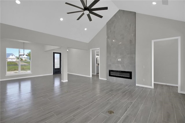 unfurnished living room featuring ceiling fan, hardwood / wood-style floors, high vaulted ceiling, and a tile fireplace