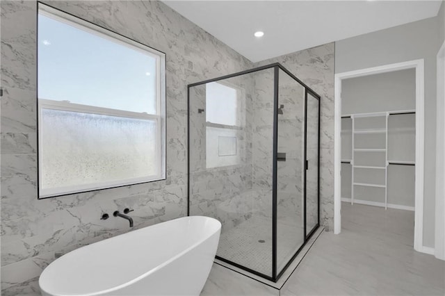 bathroom featuring a soaking tub, recessed lighting, a marble finish shower, and a walk in closet
