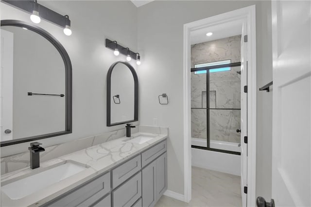 full bathroom with double vanity, shower / bath combination with glass door, marble finish floor, and a sink