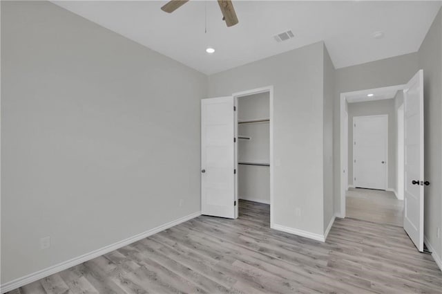 unfurnished bedroom featuring visible vents, baseboards, recessed lighting, light wood finished floors, and a walk in closet