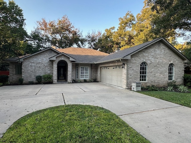 307 Stewart St, Meadowlakes, TX 78654 - ranch-style house featuring an attached garage, brick siding, concrete driveway, a shingled roof, and a front yard