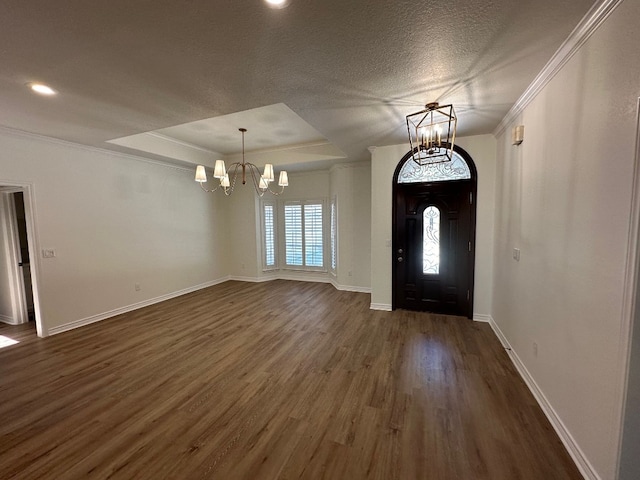 entrance foyer with a raised ceiling, ornamental molding, a textured ceiling, dark hardwood / wood-style floors, and an inviting chandelier