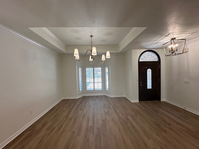 entryway featuring dark hardwood / wood-style floors, crown molding, and an inviting chandelier