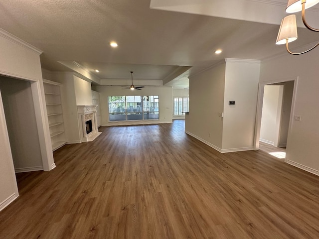 unfurnished living room featuring ceiling fan, dark hardwood / wood-style flooring, crown molding, built in features, and a textured ceiling