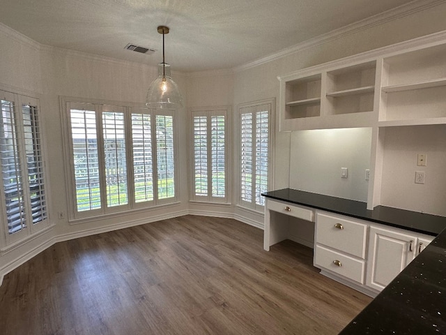 unfurnished office with ornamental molding, a textured ceiling, built in desk, and dark hardwood / wood-style floors