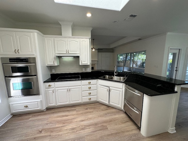 kitchen with white cabinets, stainless steel double oven, sink, light hardwood / wood-style flooring, and backsplash