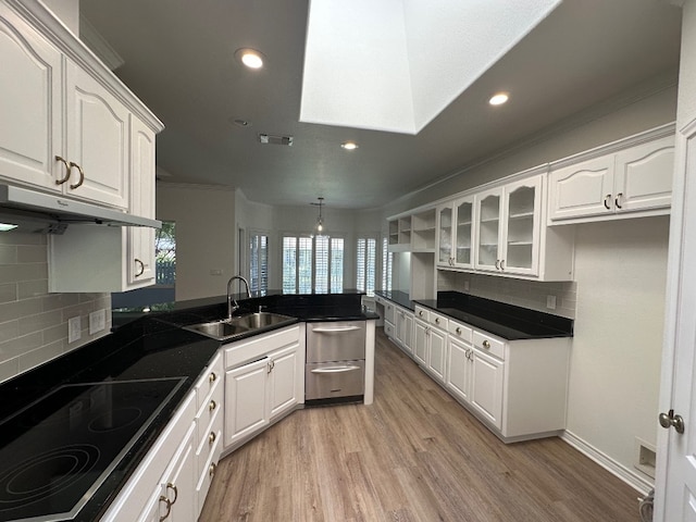 307 Stewart St, Meadowlakes, TX 78654 - kitchen with a sink, a peninsula, black electric stovetop, under cabinet range hood, and dark countertops