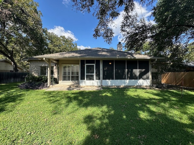 back of property with a sunroom and a lawn