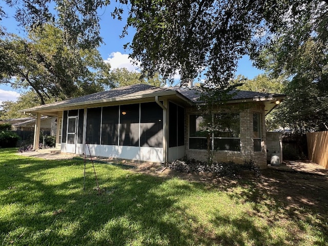 back of house with a sunroom and a lawn