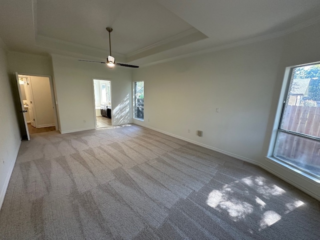 unfurnished living room featuring ornamental molding, light carpet, ceiling fan, and a raised ceiling