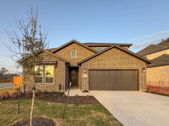 view of front of home featuring a garage, brick siding, driveway, and fence