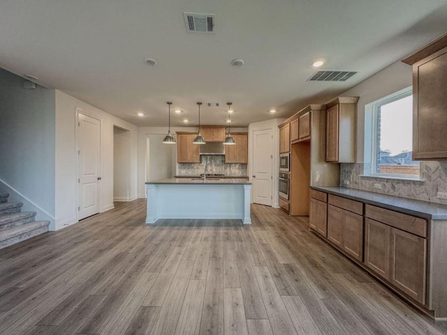 kitchen with decorative backsplash, light wood-style flooring, visible vents, and appliances with stainless steel finishes