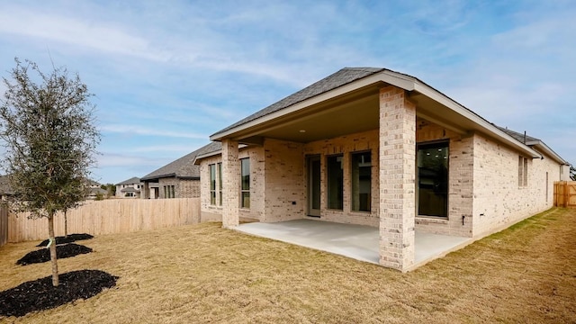 rear view of property with a yard, a fenced backyard, brick siding, and a patio