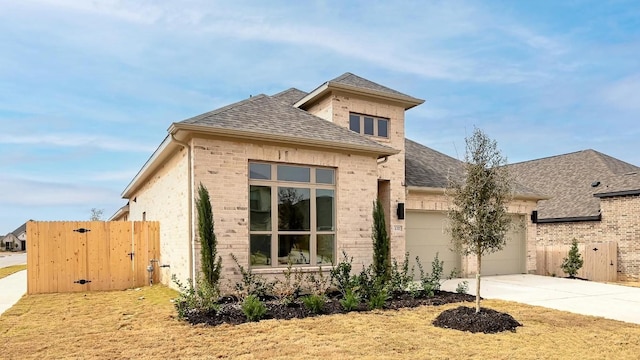 view of front facade featuring driveway, brick siding, roof with shingles, and an attached garage