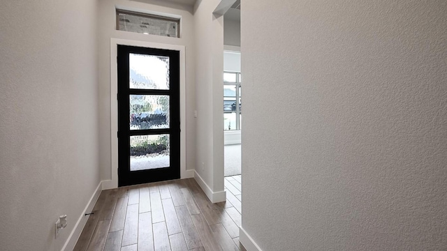 entryway featuring baseboards, wood finished floors, and a textured wall