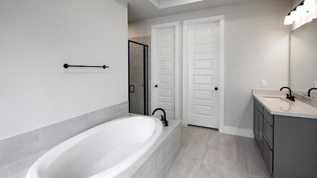 full bath featuring a stall shower, a garden tub, vanity, and baseboards