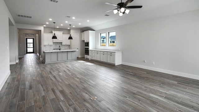 kitchen with open floor plan, tasteful backsplash, wood finished floors, and visible vents