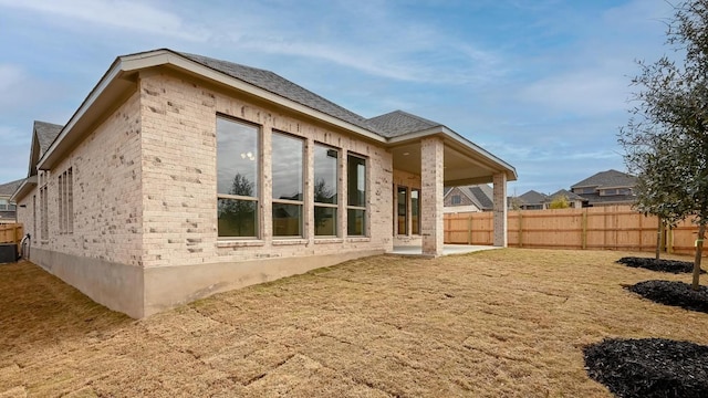 view of property exterior with a patio, brick siding, and fence