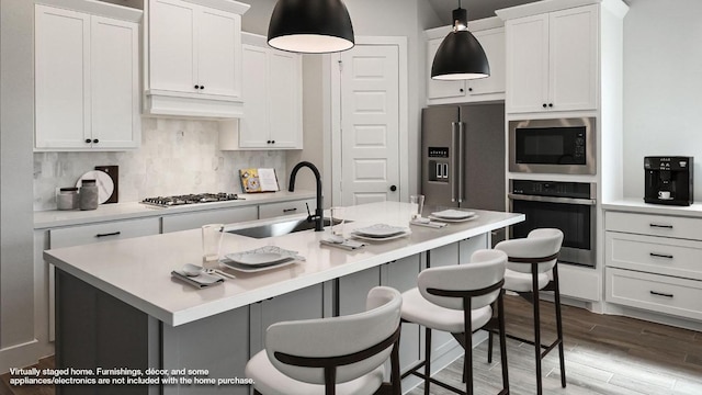 kitchen with appliances with stainless steel finishes, a kitchen bar, a sink, and white cabinets