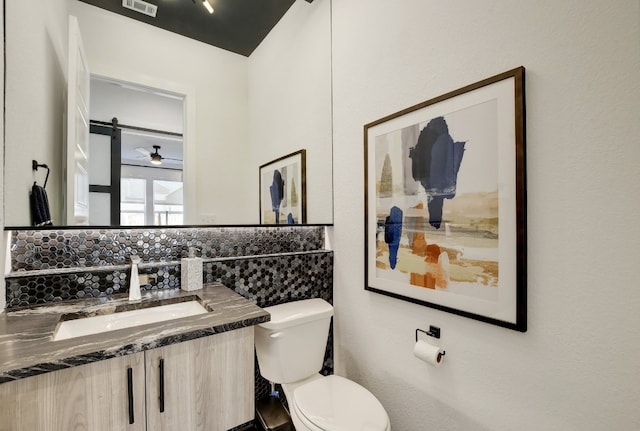 bathroom with vanity, toilet, and tasteful backsplash