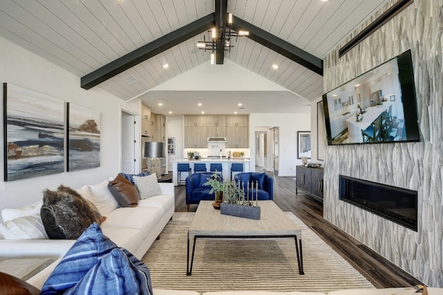 living room with vaulted ceiling with beams, an inviting chandelier, a tiled fireplace, and dark wood-type flooring