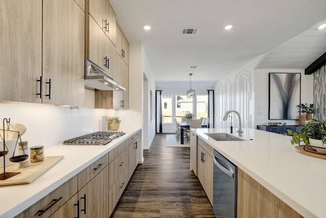 kitchen with stainless steel appliances, light brown cabinets, sink, dark hardwood / wood-style flooring, and pendant lighting