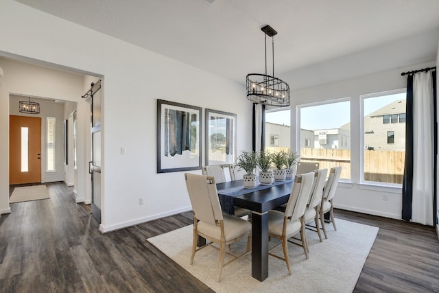 dining area featuring dark wood-type flooring, a barn door, and a healthy amount of sunlight