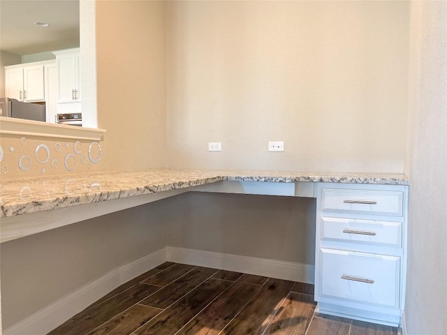 6008 Genova Pl, Round Rock, TX 78665 - kitchen with dark wood-style flooring, built in desk, white cabinetry, refrigerator, and light stone counters