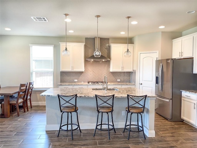 6008 Genova Pl, Round Rock, TX 78665 - kitchen featuring wall chimney range hood, appliances with stainless steel finishes, dark wood finished floors, a kitchen island with sink, and backsplash