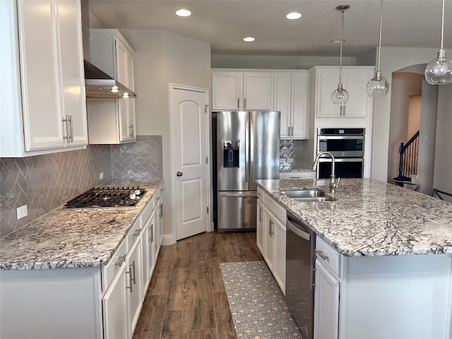 kitchen featuring an island with sink, hanging light fixtures, dark wood-type flooring, white cabinetry, and appliances with stainless steel finishes