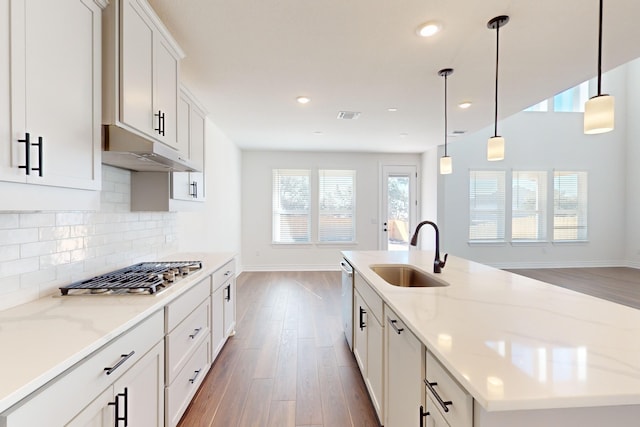 kitchen featuring pendant lighting, light stone countertops, white cabinetry, and sink