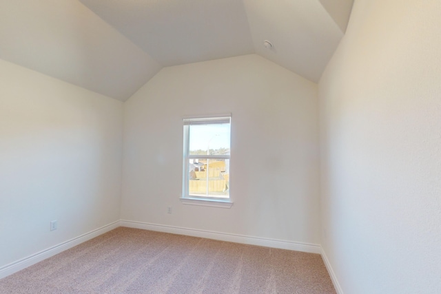 carpeted spare room featuring vaulted ceiling