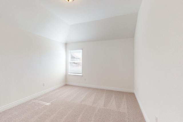 spare room with light carpet and vaulted ceiling