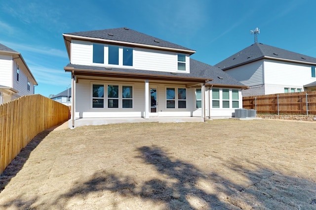 rear view of property featuring a yard, central AC, and a patio area