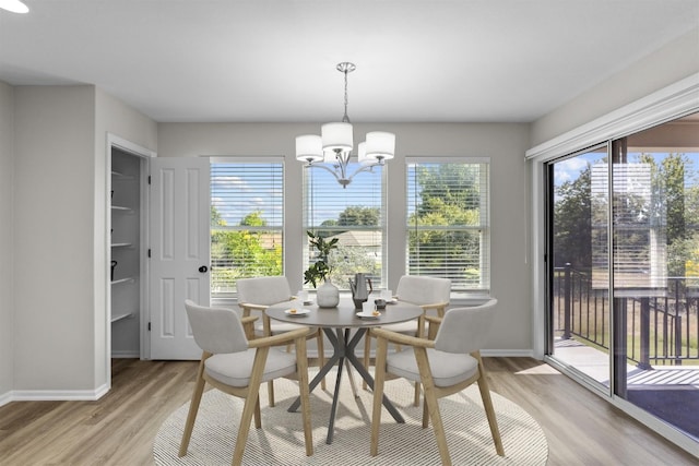 dining area with a wealth of natural light, an inviting chandelier, and light hardwood / wood-style flooring