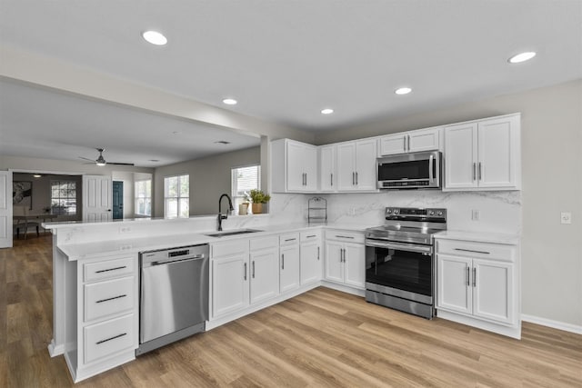 kitchen with stainless steel appliances, sink, light wood-type flooring, and white cabinetry