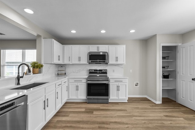 208 Bright Leaf Trl, Georgetown, TX 78633 - kitchen with appliances with stainless steel finishes, a sink, light wood-style flooring, recessed lighting, and white cabinets